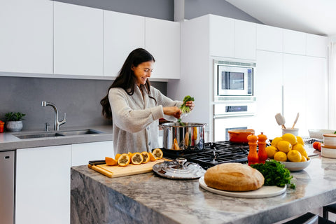 Woman preparing healthy food in kitchen — building a simple daily supplement routine